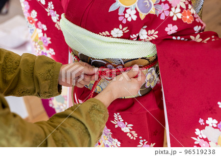 若い女性に振袖の着付けしているところ 96519238