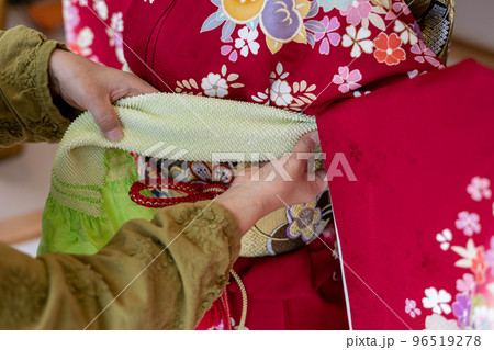 若い女性に振袖の着付けしているところ 96519278