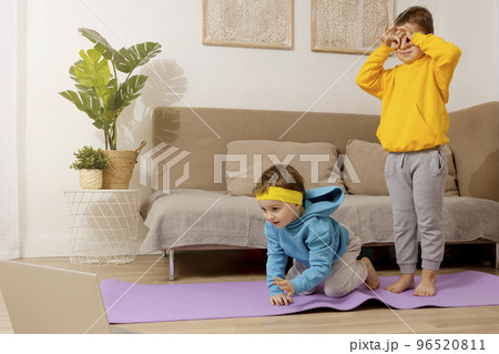 Two active, little caucasian kids doing fitness exercises at home. Brothers relationship. Children spending time together, having fun during sport. Boys make training, looking at computer. Two active, little caucasian kids doing fitness exercises at home. Brothers relationship. Children spending time together, having fun during sport. Boys make training, looking at computer. 96520811