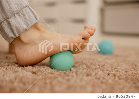 Woman doing flatfoot correction gymnastic exercise using massage ball. Myofascial relaxation of foot muscles. Hallux valgus. Pain. Identification of flat feet. Self care practices at home, healthcare. 96520847