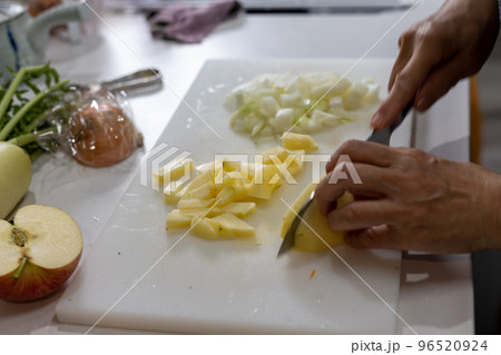 台所で玉ねぎとリンゴを切っている女性の手元 96520924