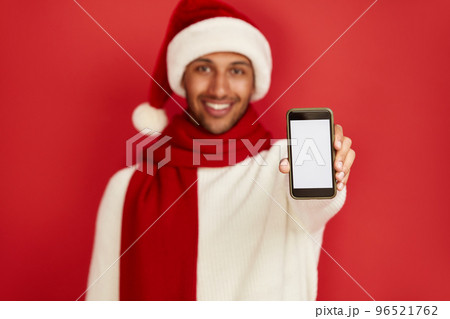 Happy Man Using Smartphone. Multiracial Guy Santa Hat Smiling Showing Cellphone 96521762
