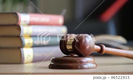 Judge gavel or hammer on sounding block and stack of law books on table 96522915