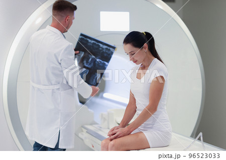 Practitioner looking at mri picture, female patient at medical consultation 96523033