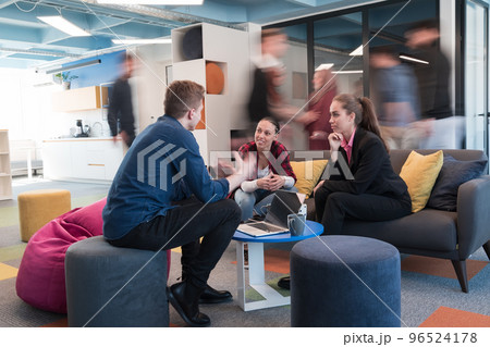 Multiethnic startup business team on meeting in a modern bright open space coworking office. Brainstorming, working on laptop. Group of coworkers walking around in motion blur. 96524178