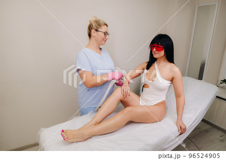 A cosmetologist performs a laser hair removal procedure in the office 96524905