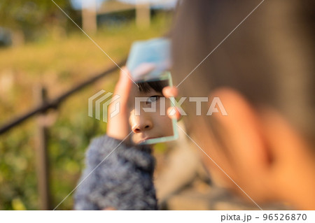 秋の公園で遊んでいる子供が手鏡を見ている様子 96526870