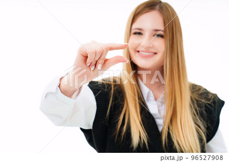 an attractive blonde in a black vest shows her fingers a little sign. an attractive blonde in a black vest shows her fingers a little sign. 96527908