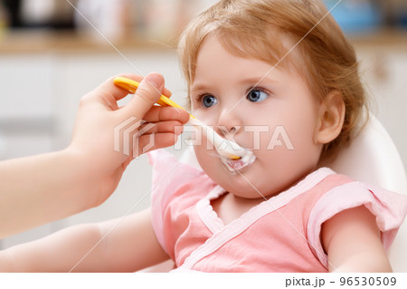 feeds baby with a spoon porridge. A little girl 96530509