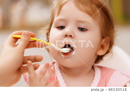 feeds baby with a spoon porridge. A little girl 96530518