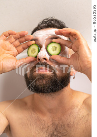 man put on cucumber on face in bath at home 96530595