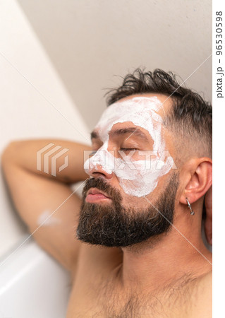 man with face mask relaxing in bath at home 96530598