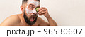 Funny man with cucumber and beauty mask on face in bath at home 96530607