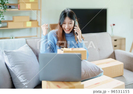 Starting small business entrepreneur of independent Asian woman smiling using computer laptop with cheerful success of online marketing package box items and SME delivery concept. 96531155