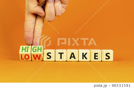 High or low stakes symbol. Concept words High stakes and Low stakes on wooden cubes. Businessman hand. Beautiful orange table orange background. Business high or low stakes concept. Copy space. High or low stakes symbol. Concept words High stakes and Low stakes on wooden cubes. Businessman hand. Beautiful orange table orange background. Business high or low stakes concept. Copy space. 96531591