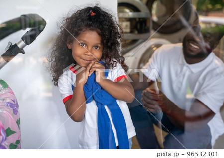 Male loading laundry into a washer assisted by his child 96532301