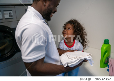 Joyful young father and his daughter at the laundromat 96532352