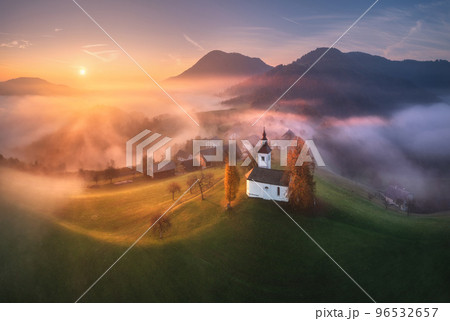 Aerial view of small church on the hill over pink low clouds Aerial view of small church on the hill over pink low clouds 96532657