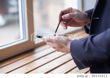 Mobile phone and stylus in male hands 96535013