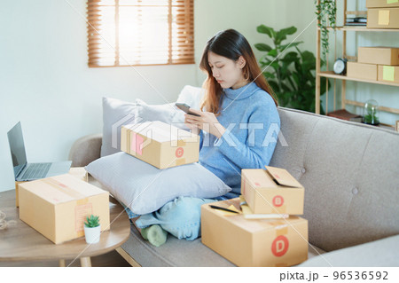 Starting small business entrepreneur of independent Asian woman smiling using computer laptop with cheerful success of online marketing package box items and SME delivery concept. 96536592
