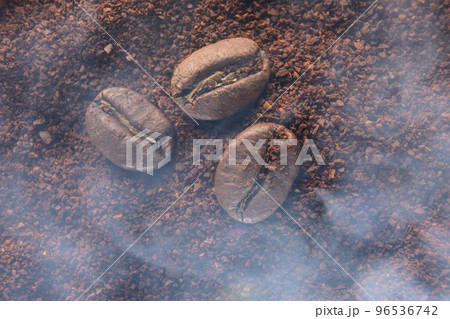 Three coffee beans lie on ground coffee close-up. 96536742