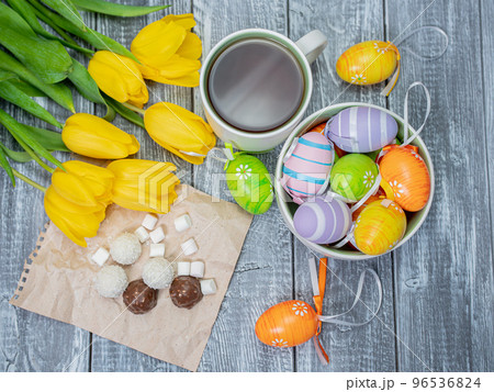 Spring Easter morning with a cup of tea on a wooden table. Yellow tulips and painted Easter eggs 96536824