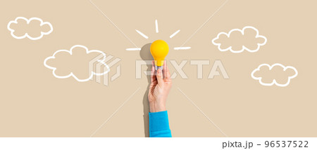 Person holding a light bulb with cloud sketches 96537522
