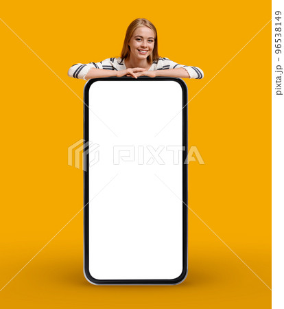 Cool App. Smiling Young Woman Leaning At Big Smartphone With Blank Screen Cool App. Smiling Young Woman Leaning At Big Smartphone With Blank Screen 96538149