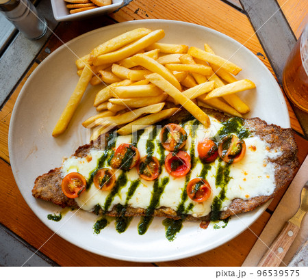 Beef steak with mozzarella, tomatoes and pesto served with fries Beef steak with mozzarella, tomatoes and pesto served with fries 96539575