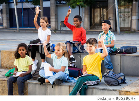 Schoolchildren with hands raised during lesson outside school 96539647