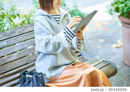 カジュアルな服装でタブレットPCを操作する女性 96540886