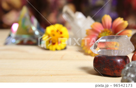 Quartz Crystal Balanced on Bloodstone With Flowers in Background Shallow DOF 96542173