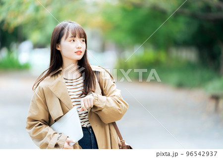 パソコンを持って歩く若い女性 96542937