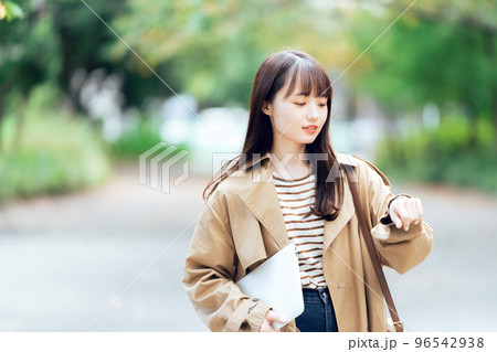 パソコンを持って歩く若い女性 96542938
