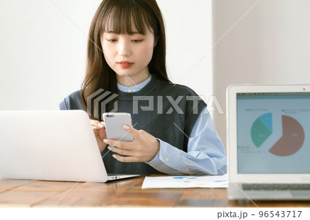 オフィスでスマホ操作する若い女性 96543717