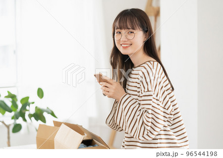 スマホアプリで不要品を売る若い女性 スマホアプリで不要品を売る若い女性 96544198