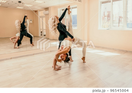 Well looking middle aged woman with black hair, fitness instructor in leggings and tops doing stretching and pilates on yoga mat near the mirror. Female fitness yoga routine concept. Healthy lifestyle 96545004