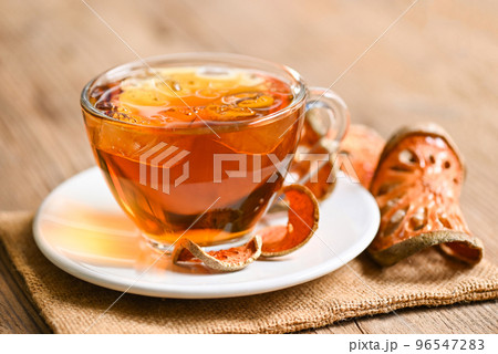 Bael tea on glass with dried bael slices on wooden background, Bael  juice - Dry bael fruit tea for health - Aegle marmelos 96547283