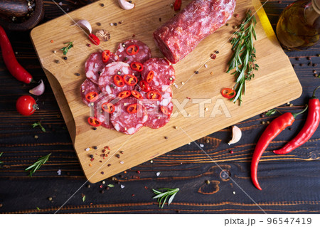 Traditional salami sausage on wooden cutting board with spices 96547419