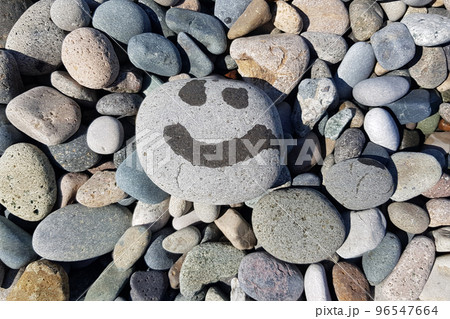Closeup of  grey pebbles on a beach with painting of smile 96547664