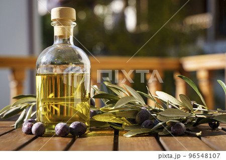 Olive oil with olive tree branch background. Natural oil for food or cosmetics from natural ingredients. Healthy food, cosmetics concept. 96548107