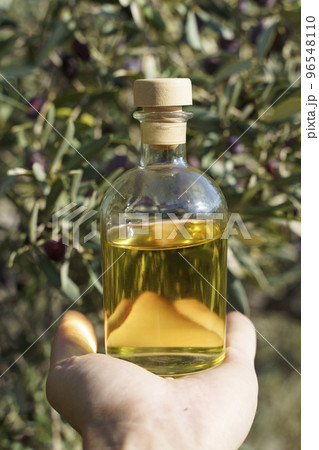 Olive oil with olive tree branch background. Natural oil for food or cosmetics from natural ingredients. Healthy food, cosmetics concept. Olive oil with olive tree branch background. Natural oil for food or cosmetics from natural ingredients. Healthy food, cosmetics concept. 96548110