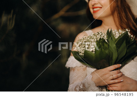 Portrait of a beautiful woman in a white dress and a hat with lilies of the valley. A girl in nature. Spring flowers Portrait of a beautiful woman in a white dress and a hat with lilies of the valley. A girl in nature. Spring flowers 96548195