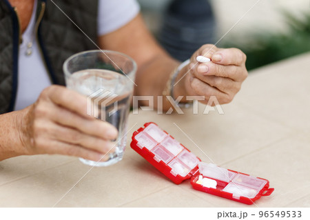 Head shot portrait happy woman holds pill glass of water, takes daily medicine vitamin D, omega 3 supplements, skin hair nail strengthen and beauty, medication for health care concept 96549533