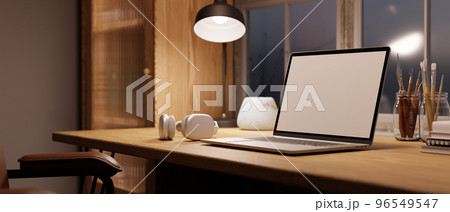 Cozy Scandinavian home workspace with laptop mockup, light from table lamp on wood table. Cozy Scandinavian home workspace with laptop mockup, light from table lamp on wood table. 96549547