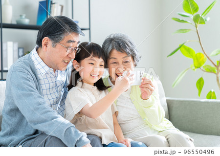 スマホを見る孫娘とシニアの夫婦 96550496