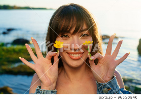 Portrait of a young woman holding flowers near her face 96550840
