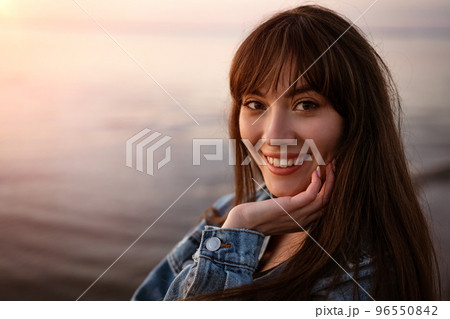 Portrait of a young woman on the background of the sea at sunset 96550842