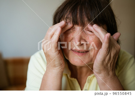 Portrait of a mature woman holding her head with her hands for headache 96550845