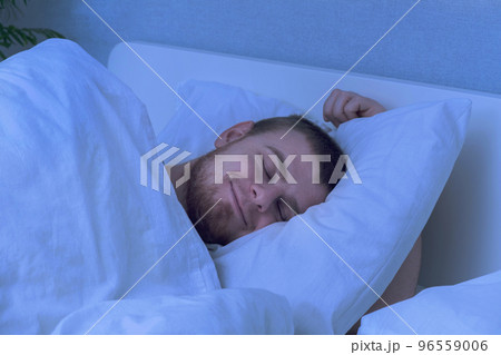 A bearded young man is night sleeping in a cozy A bearded young man is night sleeping in a cozy 96559006